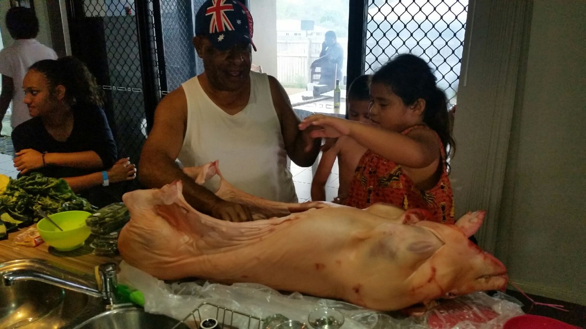 Man and girl prepare a raw pig on a table