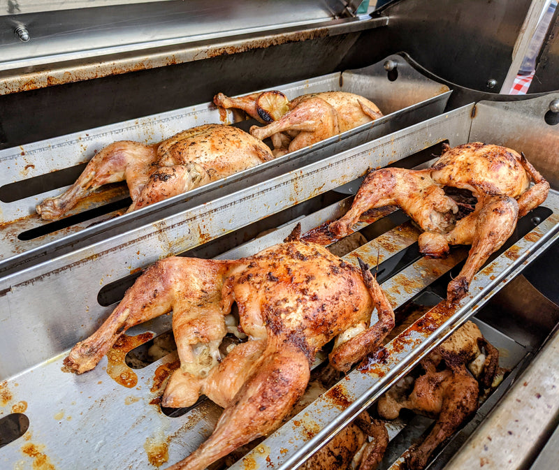 Chickens roasting in rotisserie basked on a propane cooking machine
