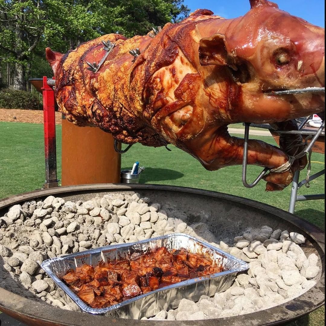 Whole pig roasting golden brown on a PigOut charcoal rotisserie over a fire