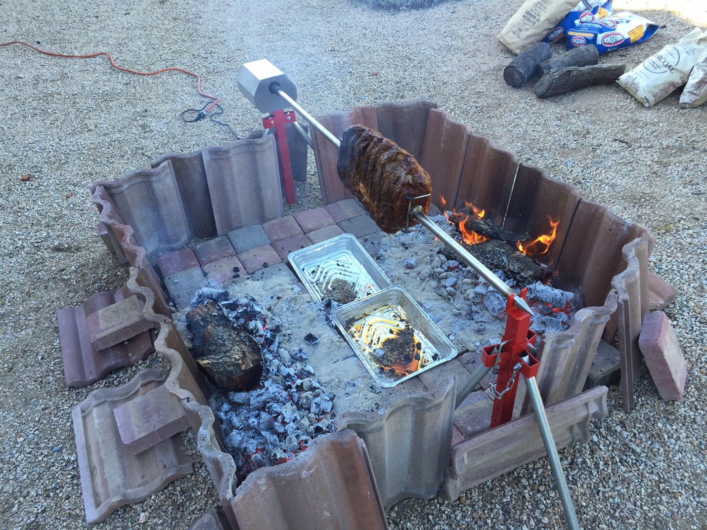Charcoal rotisserie being used over a custom firepit
