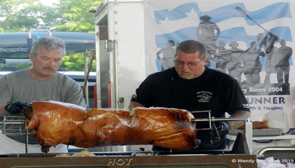 two men watching a pig roast