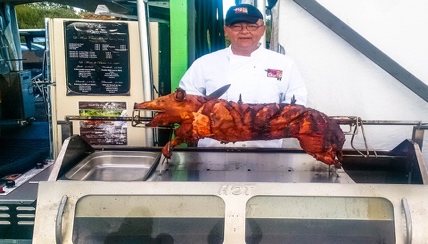 man standing in front of a roasted pig